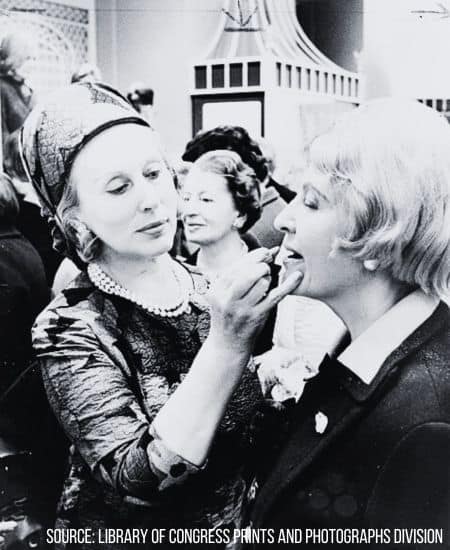 Photo of Estee Lauder applying lipstick to a female